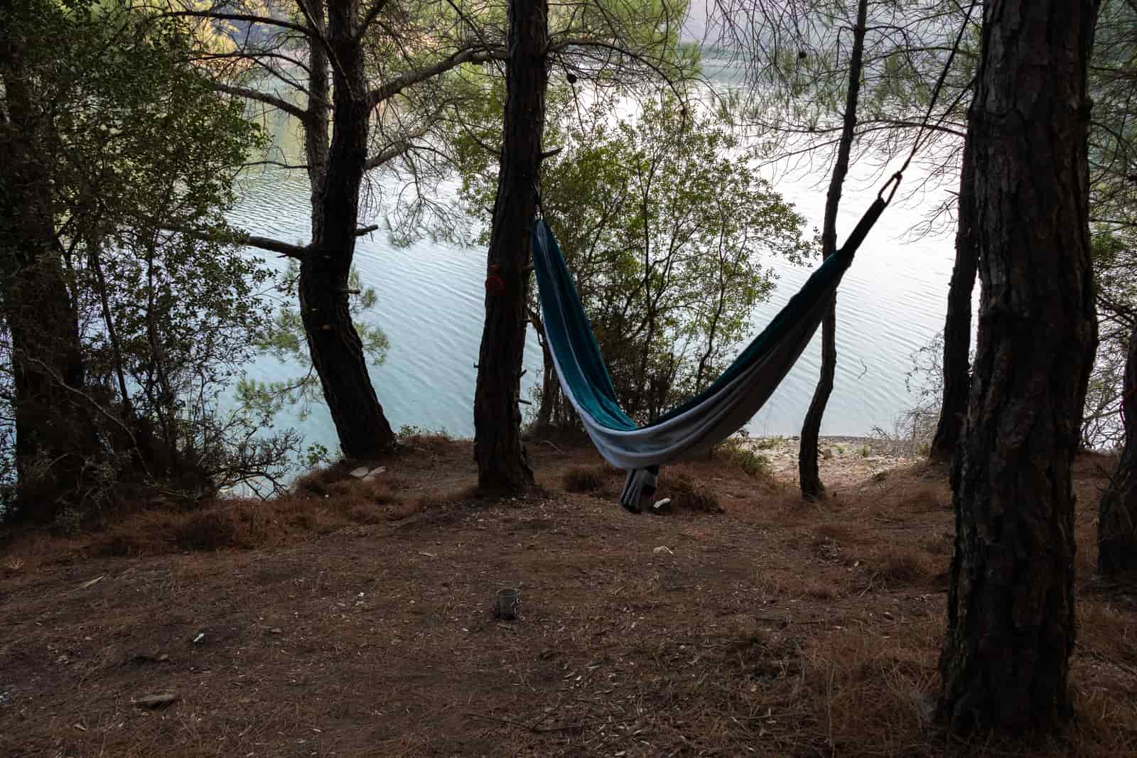 Nylon camping hammock hanging between trees in a forest
