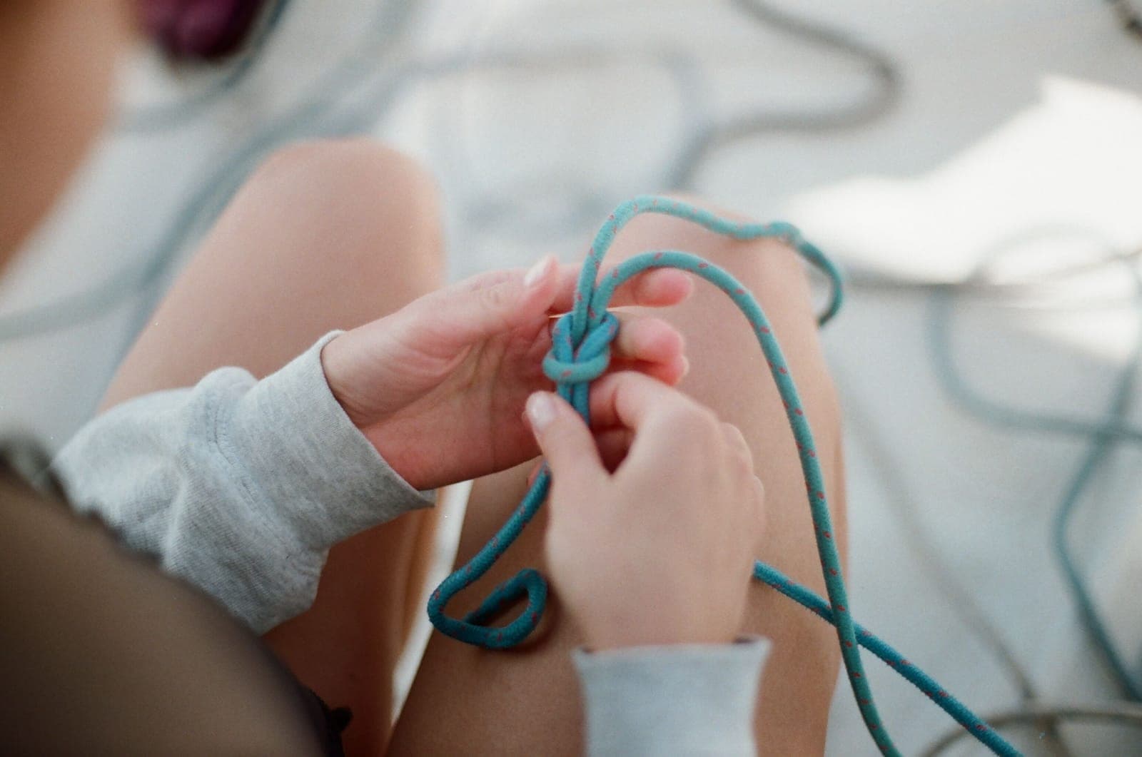 Hands tying a hammock suspension line outdoors